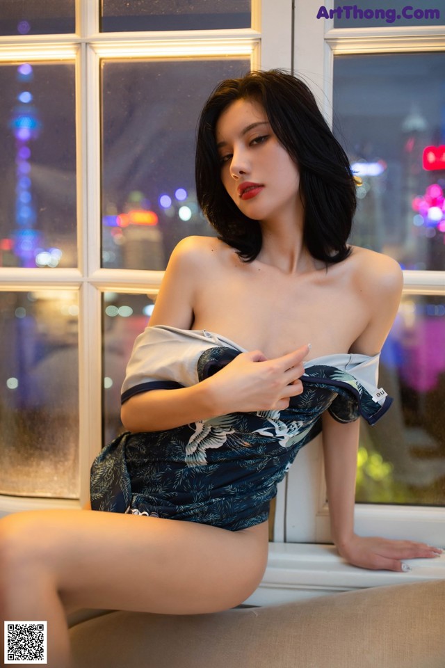 A woman sitting on a couch in front of a window.