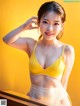 A woman in a yellow bra and white panties posing for a picture.