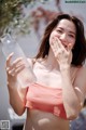 A woman in a pink bikini holding a bottle of water.