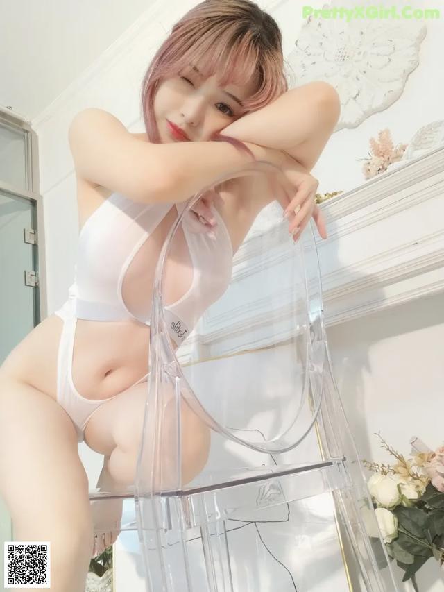 A woman in a white lingerie sitting on a clear chair.