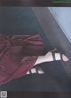 A woman in a maroon dress and black sandals laying on the floor.