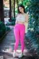 A woman in a white top and pink leggings posing for a picture.