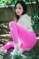 A woman in pink leggings sitting on a rock.