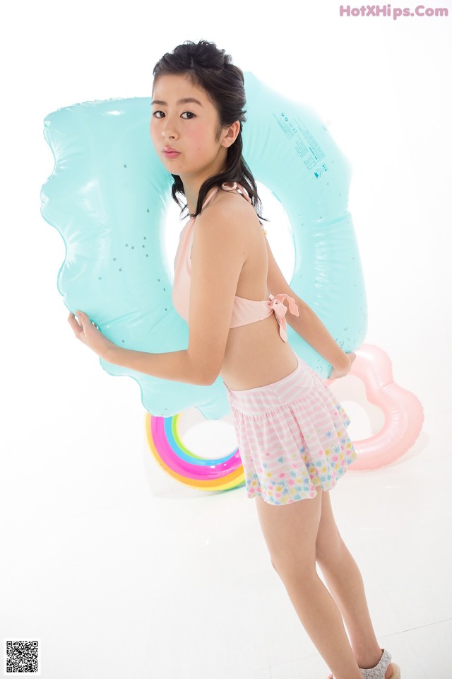 A young woman in a pink bikini holding an inflatable ring.