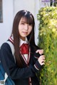 A young woman in a school uniform leaning against a wall.