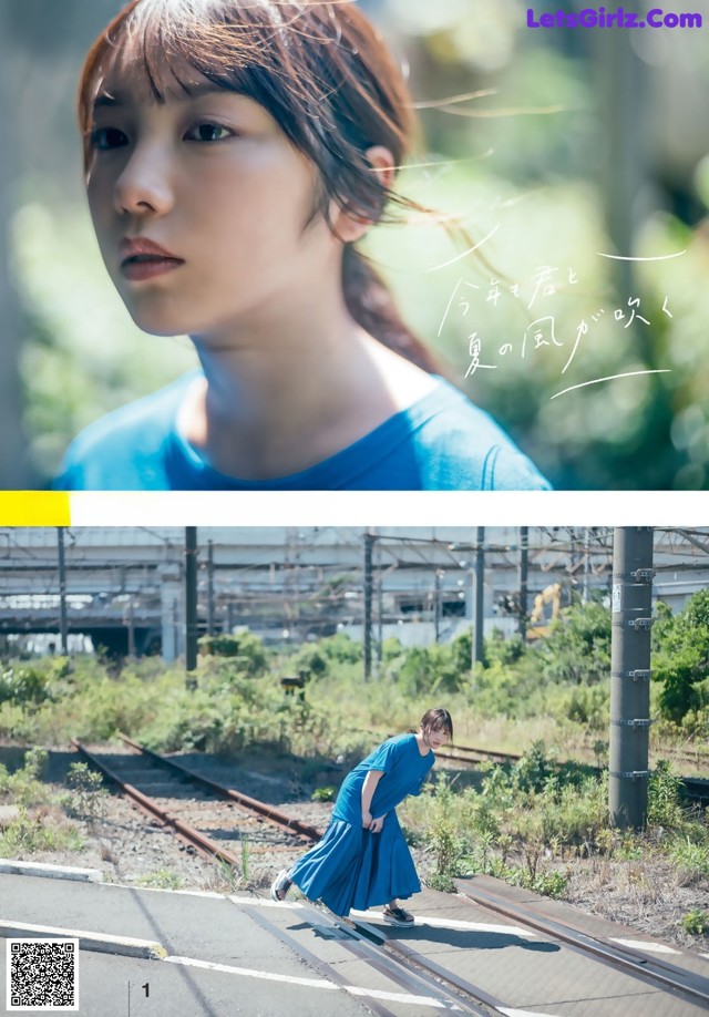 A woman in a blue dress standing on a train track.