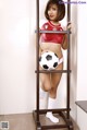 A woman in a red and white outfit holding a soccer ball.